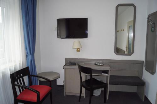 a room with a desk and two chairs and a mirror at Hotel Merian in Cologne