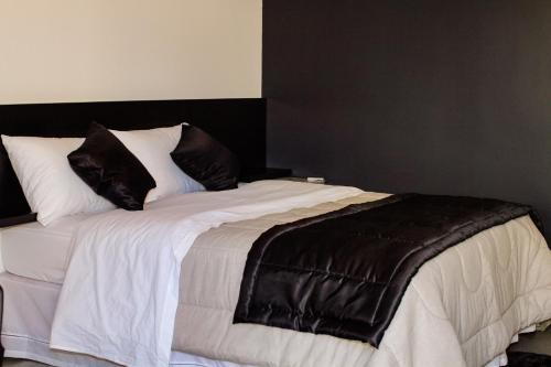 a bed with a black and white blanket and pillows at Concept Design Hostel & Suites in Foz do Iguaçu