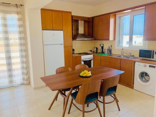 a kitchen with a wooden table and some chairs at Helios Apartments - Beach of Lachania Rhodes in Lakhania