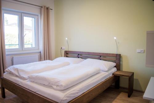 uma cama com lençóis brancos num quarto com uma janela em Apartmán Laura, Frymburk em Frymburk