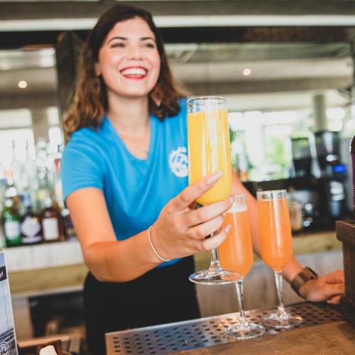a woman holding up two glasses of beer at Numero Uno Beach House in San Juan