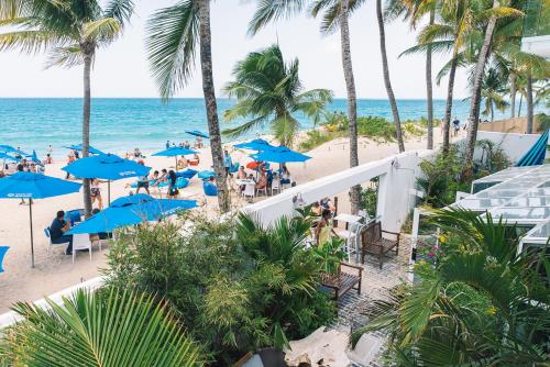 a beach with people sitting under blue umbrellas at Numero Uno Beach House in San Juan