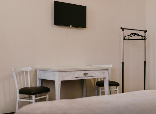 a white desk with two chairs and a television on a wall at Brick walls in Gori