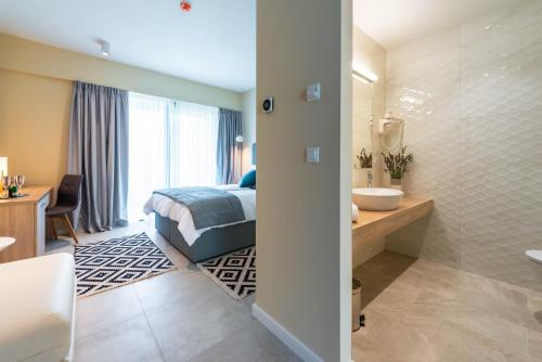 a bedroom with a bed and a bathroom with a sink at Hotel Seventh in Cavtat