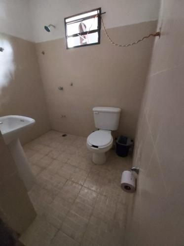 a bathroom with a toilet and a sink and a window at Delmar Hostal in Bacalar