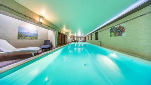 a swimming pool with blue water in a building at Borhotel Sziluett Farkasmály in Gyöngyös