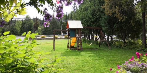 a park with a playground in the grass at Motel Des Pays D'En Haut in Val-David