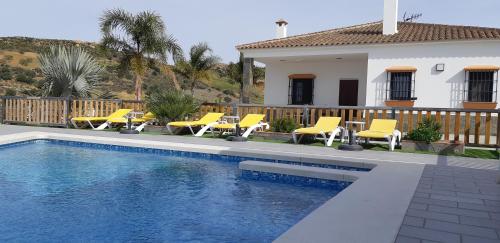 una piscina con sillas amarillas y una casa en Villa Rural El Mirador, en Álora