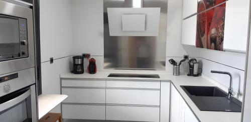 a white kitchen with a sink and a microwave at Villa Rural El Mirador in Alora