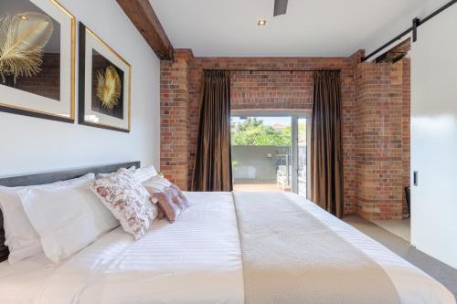 um quarto com uma cama grande e uma parede de tijolos em Luxury 3 brm 2 bath Woolstore apt with Courtyard em Brisbane