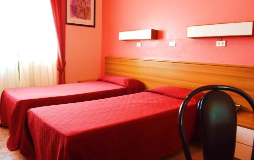 two beds in a room with red walls at Hotel Rosy in Arluno