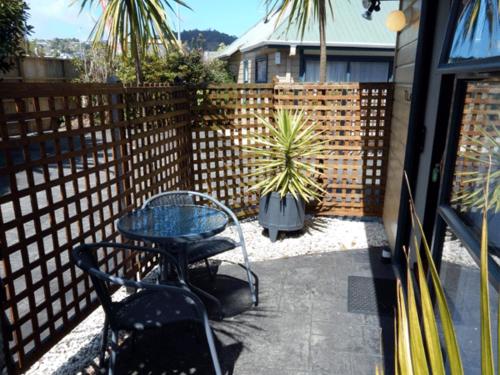 d'une terrasse avec une table, des chaises et une clôture. dans l'établissement Cheviot Park Motor Lodge, à Whangarei