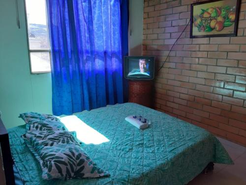 a bedroom with a bed and a tv and a brick wall at Habitaciones Altos de Cooservicios in Tunja