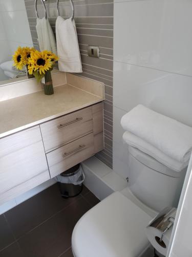 een badkamer met een wit toilet en een vaas met bloemen bij DEPARTAMENTO EDIFICIO MARES DE MONTEMAR in Concón