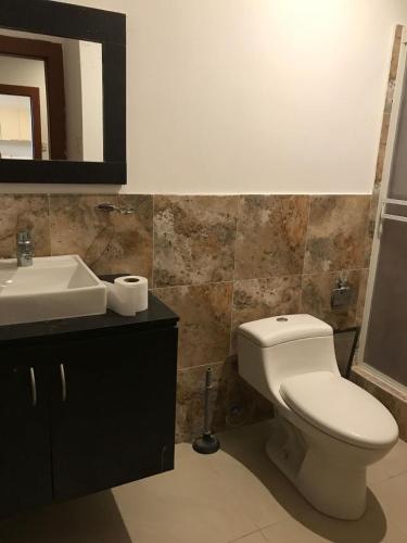 a bathroom with a white toilet and a sink at The Heights in Montañita in Montañita