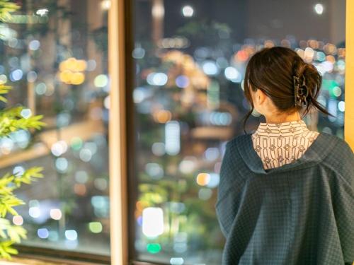a woman looking out a window at a city at Hotel Nagasaki in Nagasaki