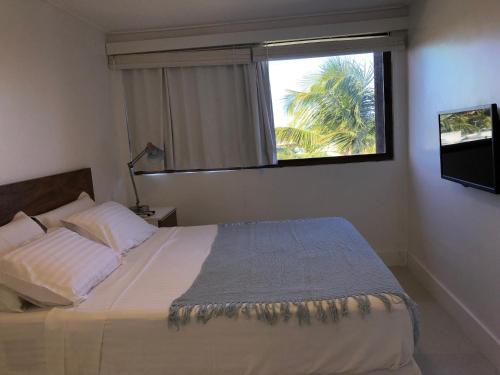 a bedroom with a large bed with a window at Cobertura Barra de São Miguel in Barra de São Miguel