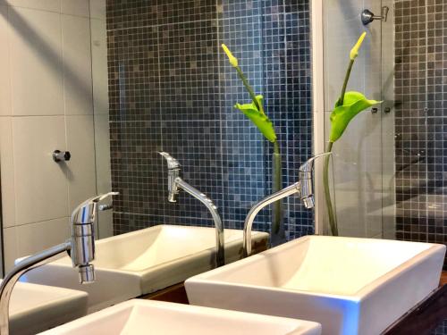 a bathroom with two sinks and a shower with green umbrellas at Cobertura Barra de São Miguel in Barra de São Miguel