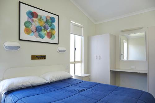 ein Schlafzimmer mit einem blauen Bett und einem Spiegel in der Unterkunft Hat Head Holiday Park in Hat Head