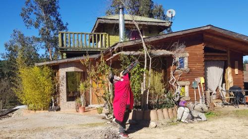 a woman is standing outside of a log house at Cabañas Rukas Licantén in Licantén