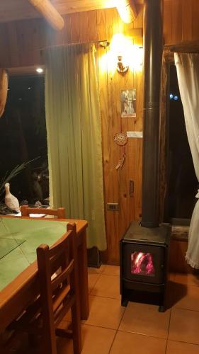 a stove in a room with a table and a bed at Cabañas Rukas Licantén in Licantén