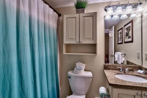 a bathroom with a toilet and a sink and a shower curtain at Pelican Beach Resort Destin in Destin