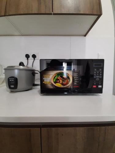 eine Mikrowelle auf einer Küchentheke mit einer Kanne Essen in der Unterkunft MS Vacation Home (Muslim Homestay) in Cameron Highlands