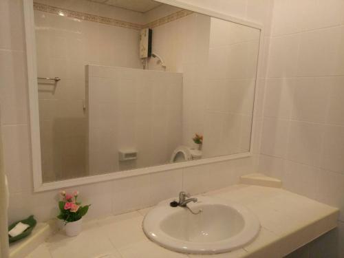 ein weißes Badezimmer mit einem Waschbecken und einem Spiegel in der Unterkunft โรงแรมเวลลิงตัน in Ban Chak Phai