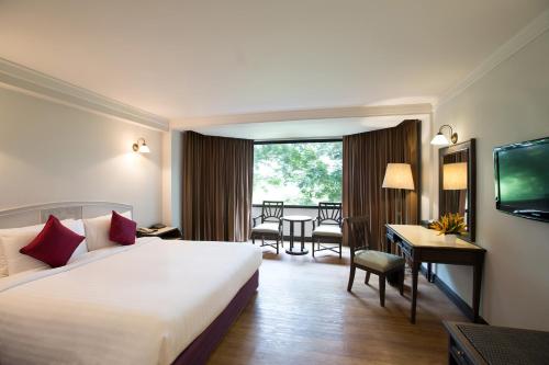um quarto de hotel com uma cama grande e uma secretária em The Imperial Hotel & Convention Centre Phitsanulok em Phitsanulok