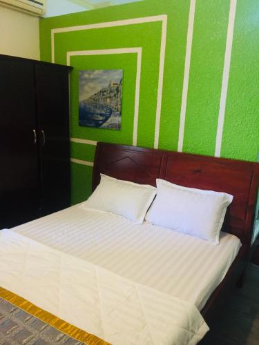 a bed in a room with a green wall at Nam Phương Hotel Sa Đéc in Sa Ðéc