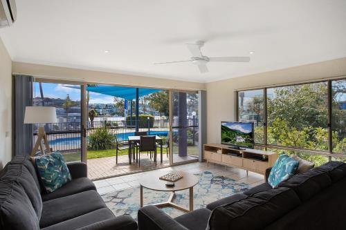 a living room with a couch and a tv at Sails Luxury Apartments Merimbula in Merimbula
