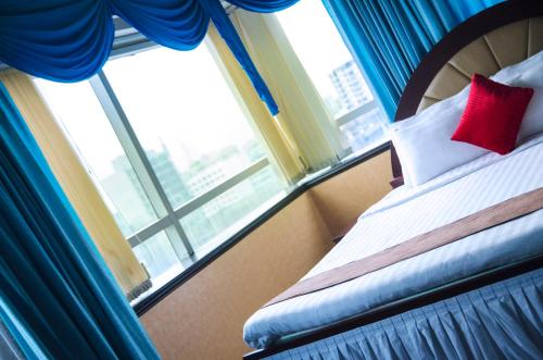 a bedroom with a bed with blue curtains and a window at Hotel 71 in Dhaka