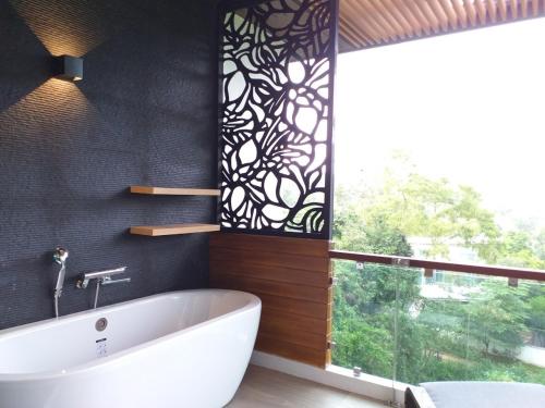 a bathroom with a white tub and a window at Reiz - Private Residence in Chiang Mai