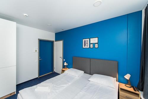a bedroom with a blue wall and a large bed at Zaliakalnio terasos apartamentai in Kaunas