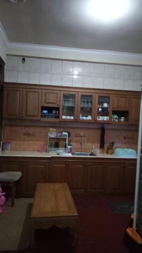 a kitchen with wooden cabinets and a sink and a table at Nusin 54 Homestay in Malang