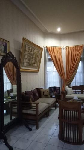 ein Wohnzimmer mit Sofas, Stühlen und Fenstern in der Unterkunft Nusin 54 Homestay in Malang