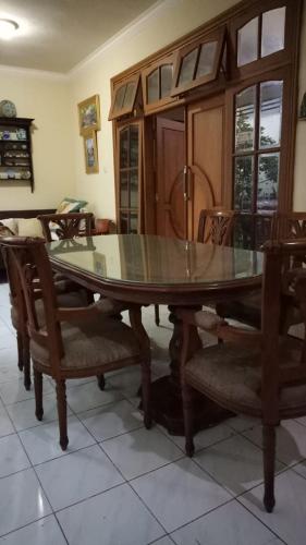 a dining room with a glass table and chairs at Nusin 54 Homestay in Malang