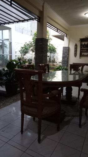 een tafel en stoelen in een kamer met een tafel en ramen bij Nusin 54 Homestay in Malang