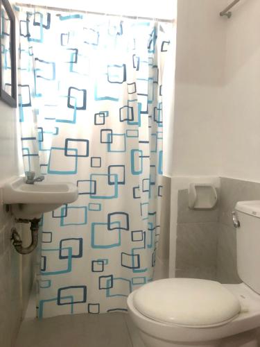 a bathroom with a toilet and a shower curtain at Paguia’s Cottages in Mambajao