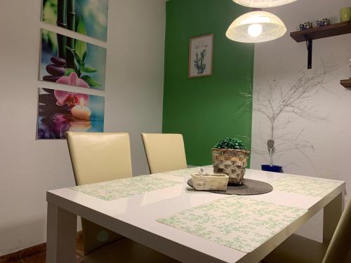 a dining room table with chairs and a green wall at Apartments Banovci in Banovci