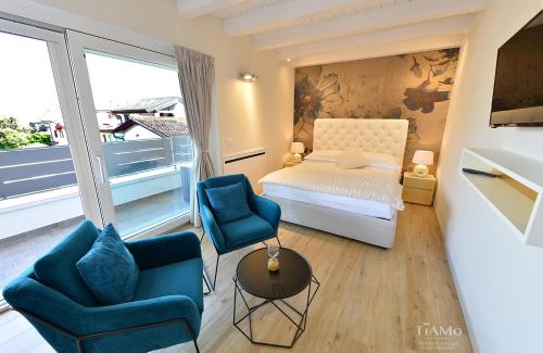 a bedroom with a bed and two blue chairs at TiAMo Modern Design Guest House in Ronchi dei Legionari