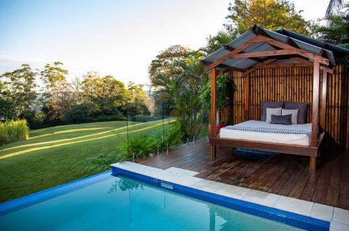 a bed in a wooden gazebo next to a swimming pool at Montville Misty View Cottages in Montville