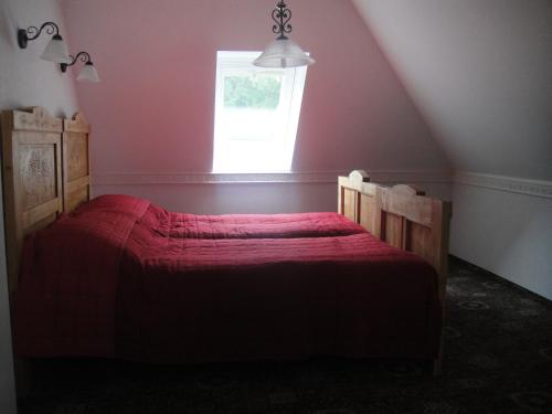 a bedroom with a red bed with a window at Sághegy Fogadó és Panzió in Celldömölk