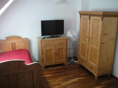 a bedroom with a bed and a tv on a wooden cabinet at Sághegy Fogadó és Panzió in Celldömölk