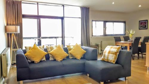 a living room with a blue couch with yellow pillows at Elegant Apartment Near SECC/HYDRO in Finnieston, Glasgow in Glasgow