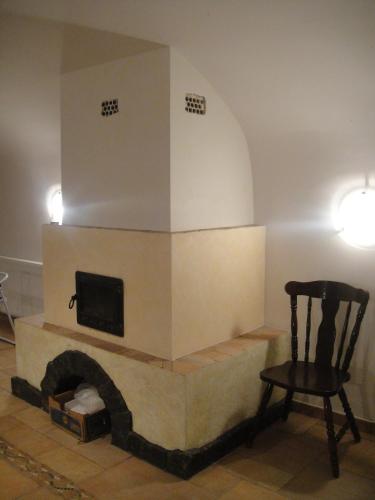 a living room with a fireplace with a tv and a chair at Sághegy Fogadó és Panzió in Celldömölk