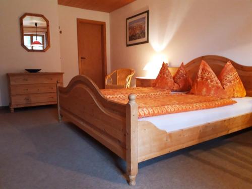 1 dormitorio con 1 cama grande de madera con almohadas de color naranja en Ferienwohnung Uschi Hipp, en Schwangau