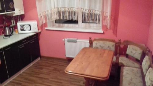 a kitchen with a table and a couch and pink walls at Хмельницьке шосе, 122а Апартаменти in Vinnytsya