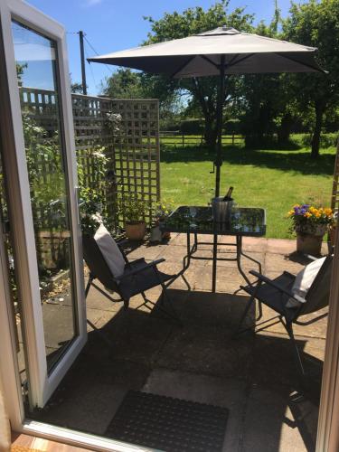 a patio with a table and chairs and an umbrella at Little Banks Barn in Ringwood