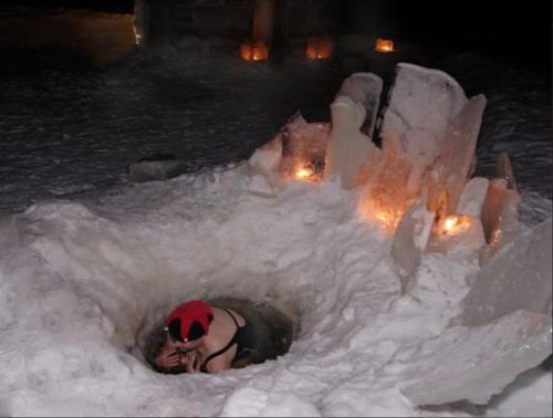 a person laying in an ice hole in the snow at Herranniemi Guesthouse in Vuonislahti